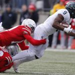 
              Ohio State defensive back Cameron Brown, bottom, and defensive back Bryson Shaw, center, tackle Michigan State running back Kenneth Walker during the first half of an NCAA college football game Saturday, Nov. 20, 2021, in Columbus, Ohio. (AP Photo/Jay LaPrete)
            