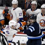 
              Winnipeg Jets' Adam Lowry (17) fights with New York Islanders' Scott Mayfield (24) in front of the Islanders' bench during the second period of NHL hockey game action in Winnipeg, Manitoba, Saturday, Nov. 6, 2021. (Fred Greenslade/The Canadian Press via AP)
            