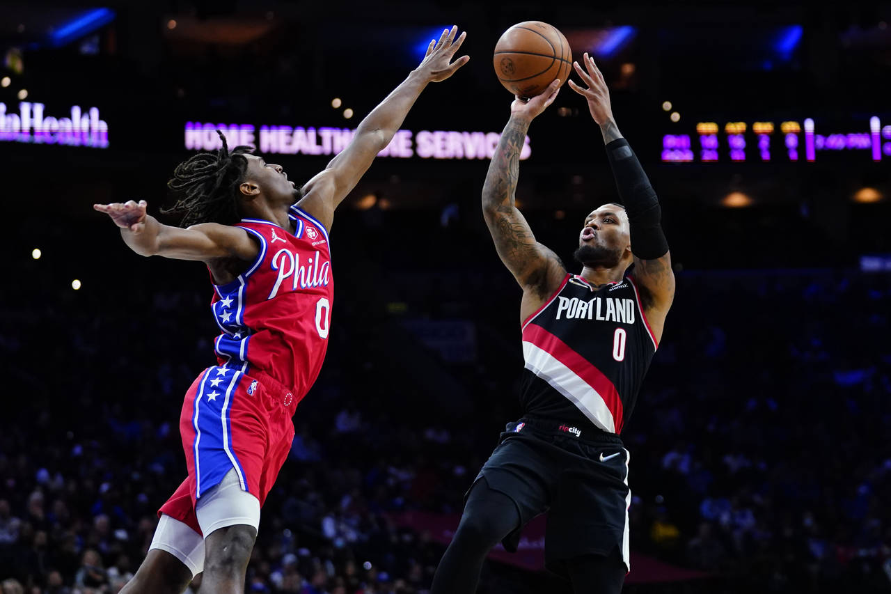 Portland Trail Blazers' Damian Lillard, right, goes up for a shot against Philadelphia 76ers' Tyres...