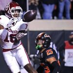 
              Oklahoma wide receiver Brian Darby (16) catches a touchdown pass in front of Oklahoma State safety Jason Taylor II (25) during the first half of an NCAA college football game Saturday, Nov. 27, 2021, in Stillwater, Okla. (AP Photo/Sue Ogrocki)
            