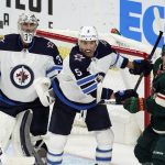 
              Winnipeg Jets' Brenden Dillon (5) comes to the aid of  Jets goalie Connor Hellebuyck (37) as he tries to keep Minnesota Wild's Kevin Fiala (22) at bay in the first period of an NHL hockey game, Friday, Nov. 26, 2021, in St. Paul, Minn. (AP Photo/Jim Mone)
            