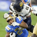 
              UCLA running back Zach Charbonnet, bottom, is grabbed by California linebacker Marqez Bimage during the first half of an NCAA college football game Saturday, Nov. 27, 2021, in Pasadena, Calif. (AP Photo/Jae C. Hong)
            