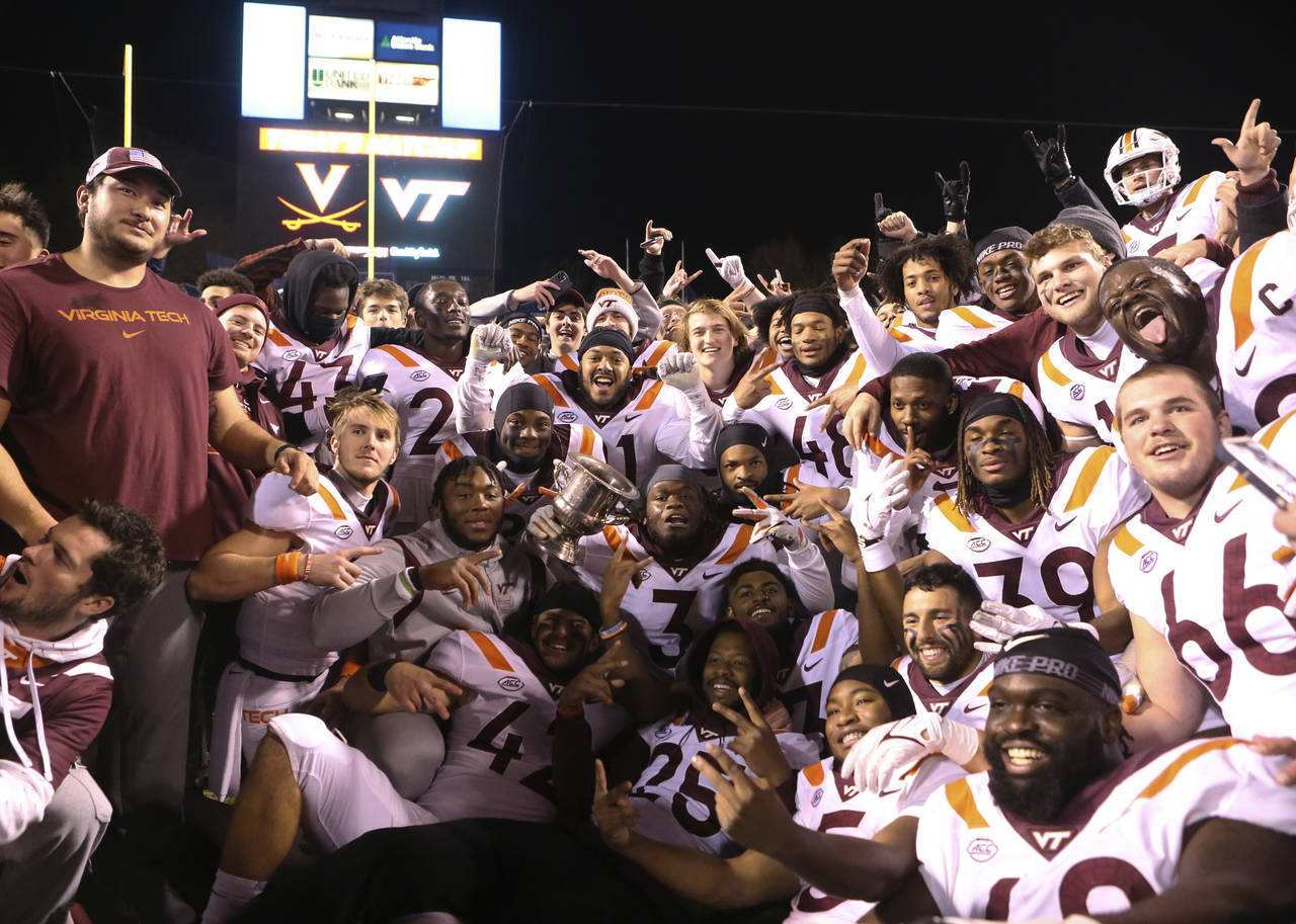 Virginia Tech players pose for a photograph after a win over Virginia in an NCAA college football g...