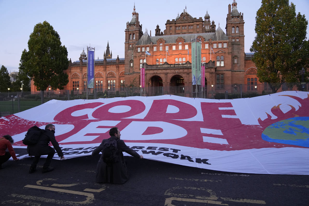 Climate activists unfurl a large banner reading "Code Red" across the street outside the Kelvingrov...