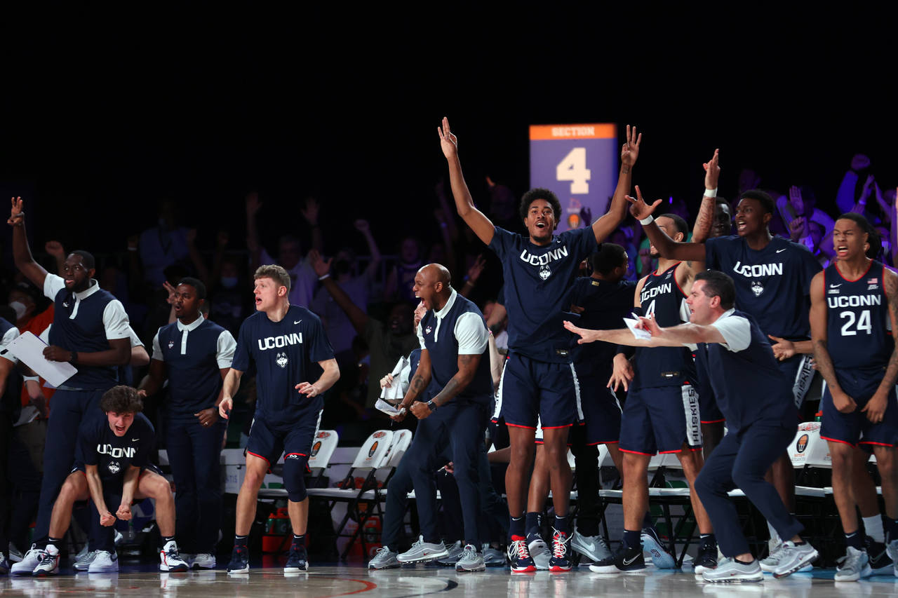 The Connecticut bench celebrates a 3-point basket against Auburn during an NCAA college basketball ...