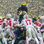 
              Michigan running back Hassan Haskins (25) leaps over Ohio State defenders for a touchdown in the second quarter of an NCAA college football game in Ann Arbor, Mich., Saturday, Nov. 27, 2021. (AP Photo/Tony Ding)
            
