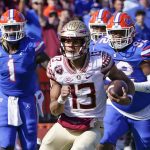 
              Florida State quarterback Jordan Travis (13) scrambles for yardage past Florida linebacker Brenton Cox Jr. (1) and defensive lineman Jalen Lee, right, during the first half of an NCAA college football game, Saturday, Nov. 27, 2021, in Gainesville, Fla. (AP Photo/John Raoux)
            