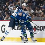
              Winnipeg Jets' Logan Stanley, back, tries to check Vancouver Canucks' Jason Dickinson during the second period of an NHL hockey game Friday, Nov. 19, 2021, in Vancouver, British Columbia. (Rich Lam/The Canadian Press via AP)
            