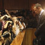 
              FILE - Photographers take photos of Olympic athlete Oscar Pistorius as he appears at a bail hearing for the shooting death of his girlfriend Reeva Steenkamp, in Pretoria, South Africa, Friday, Feb 20, 2013. Eight years after he shot dead his girlfriend, Pistorius is up for parole, but first he must meet with her parents as part of the parole procedure. A parole hearing for Pistorius was scheduled for last month and then canceled, partly because a meeting between Pistorius and Steenkamp's parents, Barry and June, had not been arranged, lawyers for both parties told The Associated Press on Monday, Nov. 8, 2021.  (AP Photo/Themba Hadebe, File)
            