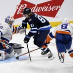 
              New York Islanders goaltender Ilya Sorokin (30) makes a save against Winnipeg Jets' Kyle Connor (81) as Islanders' Noah Dobson (8) reaches for the puck during the third period of NHL hockey game action in Winnipeg, Manitoba, Saturday, Nov. 6, 2021. (Fred Greenslade/The Canadian Press via AP)
            