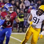 
              Kansas quarterback Jalon Daniels (6) looks to pass against West Virginia defensive lineman Sean Martin (91) during the first quarter of an NCAA college football game Saturday, Nov. 27, 2021, in Lawrence, Kan. (AP Photo/Ed Zurga)
            