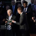 
              President Joe Biden and Milwaukee Bucks basketball player Donte DiVincenzo, center, from Newark, Del., hold onto a Bucks jersey during an event to welcome the Milwaukee Bucks basketball team to the White House to celebrate their 2021 NBA Championship, on the South Lawn of the White House in Washington, Monday, Nov. 8, 2021. Team owner Marc Lasry is at right. (AP Photo/Susan Walsh)
            