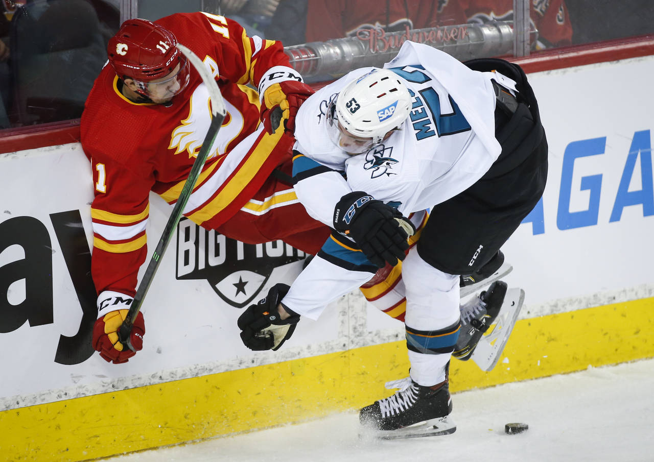 San Jose Sharks' Nicolas Meloche, right, checks Calgary Flames' Mikael Backlund during the first pe...