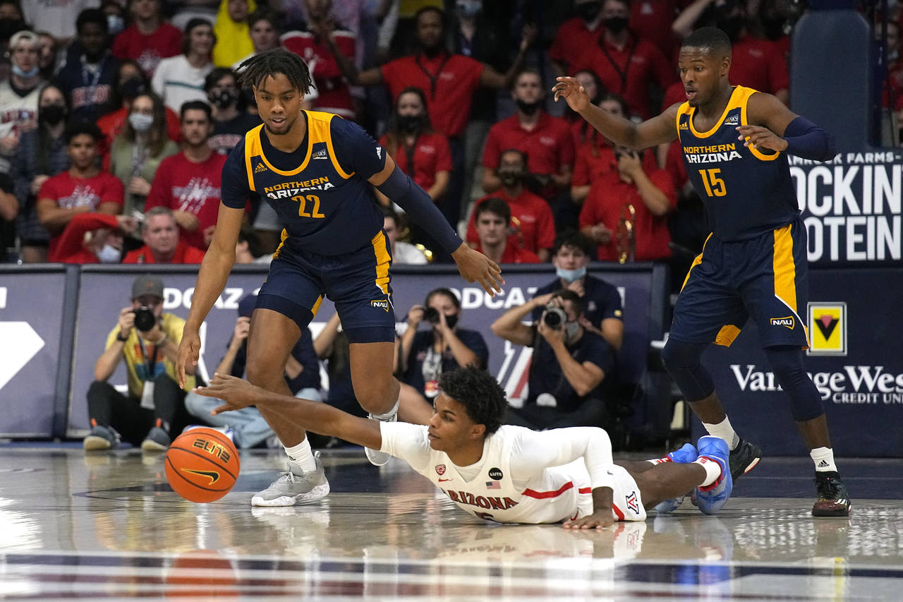 Arizona guard Justin Kier (5) dives for the loose ball in front of Northern Arizona's Wynton Brown ...