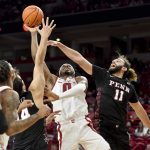 
              Arkansas guard Stanley Umude (0) shoots between Pennsylvania defenders Max Martz (14) and Michael Moshkovitz (11) during the first half of an NCAA college basketball game Sunday, Nov. 28, 2021, in Fayetteville, Ark. (AP Photo/Michael Woods)
            