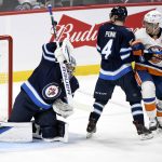
              Winnipeg Jets' goaltender Eric Comrie (1) makes a save as Neal Poink (4) defends against New York Islanders' Anders Lee (27) during the second period of NHL hockey game action in Winnipeg, Manitoba, Saturday, Nov. 6, 2021. (Fred Greenslade/The Canadian Press via AP)
            