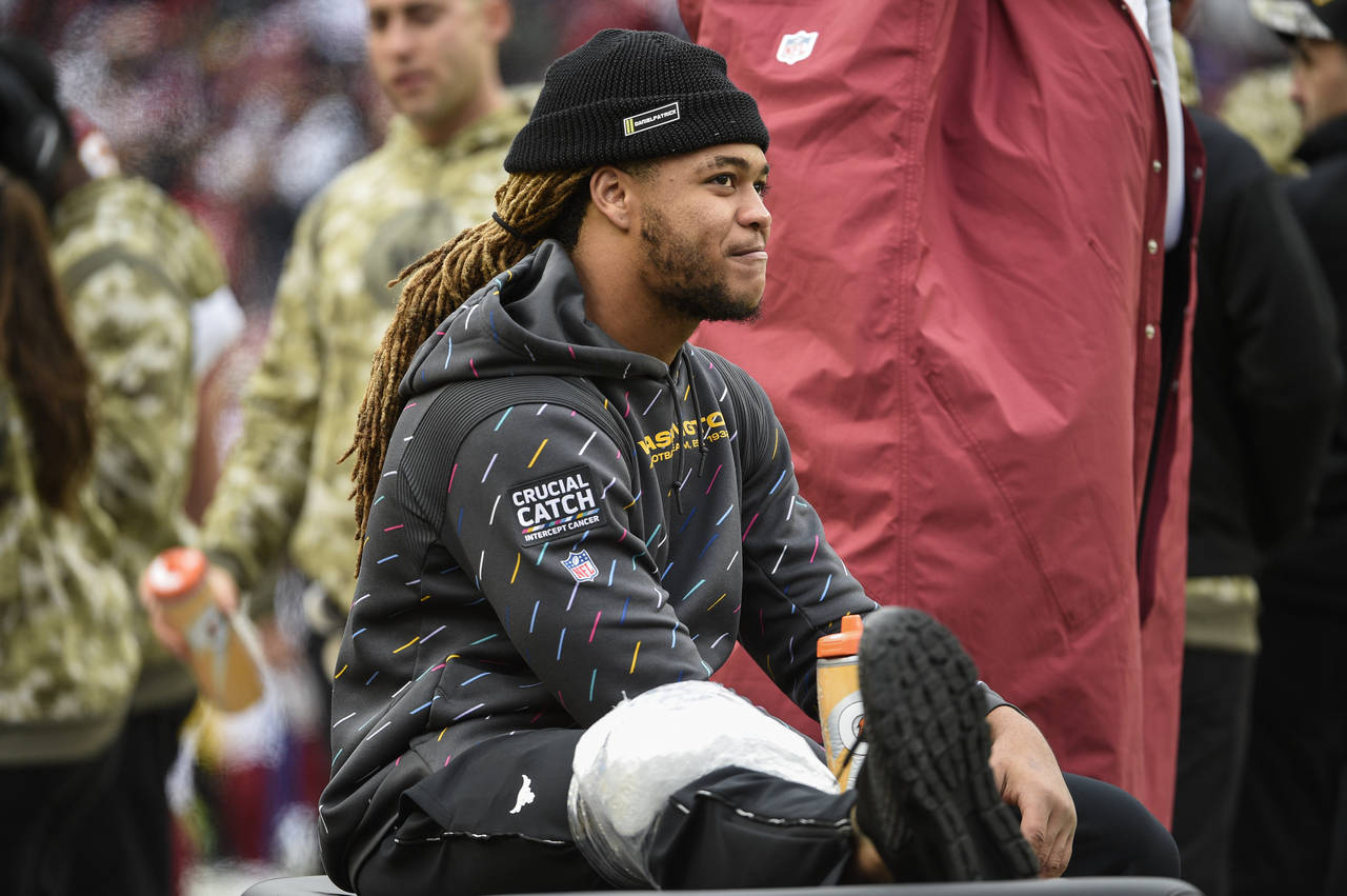 Washington Football Team defensive end Chase Young sits in the bench area with ice on his leg durin...