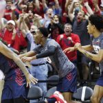 
              Dayton players and fans celebrate after their upset win over Kansas at the end of an NCAA college basketball game Friday, Nov. 26, 2021, in Lake Buena Vista, Fla. (AP Photo/Jacob M. Langston)
            