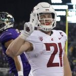 
              Washington State running back Max Borghi (21) reacts and holds up two fingers after he scored a touchdown against Washington during the second half of an NCAA college football game, Friday, Nov. 26, 2021, in Seattle. (AP Photo/Ted S. Warren)
            
