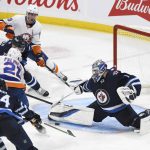
              Winnipeg Jets goaltender Eric Comrie (1) makes a save against New York Islanders' Kyle Palmieri (21) during the third period of NHL hockey game action in Winnipeg, Manitoba, Saturday, Nov. 6, 2021. (Fred Greenslade/The Canadian Press via AP)
            