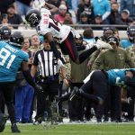
              Atlanta Falcons wide receiver Russell Gage (14) leaps over Jacksonville Jaguars cornerback Tyson Campbell, right, as defensive end Dawuane Smoot (91) comes in to make the stop during the first half of an NFL football game, Sunday, Nov. 28, 2021, in Jacksonville, Fla. (AP Photo/Chris O'Meara)
            