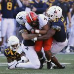 
              Oklahoma State running back Jaylen Warren (7) is dtackled by West Virginia linebackers Exree Loe (6) and Jared Bartlett (10) during the first half of an NCAA college football game in Morgantown, W.Va., Saturday, Nov. 6, 2021. (AP Photo/Kathleen Batten)
            