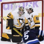 
              Pittsburgh Penguins goaltender Tristan Jarry (35) makes a save on Winnipeg Jets' Brenden Dillon (5) as Penguins' Kris Letang (58) watches during the first period of an NHL hockey game Monday, Nov. 22, 2021, in Winnipeg, Manitoba. (Fred Greenslade/The Canadian Press via AP)
            