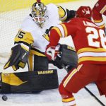 
              Pittsburgh Penguins goalie Tristan Jarry, left, makes a save against Calgary Flames' Elias Lindholm, of Sweden, during the first period of an NHL hockey game, Monday, Nov. 29, 2021 in Calgary, Alberta. (Larry MacDougal/The Canadian Press via AP)
            