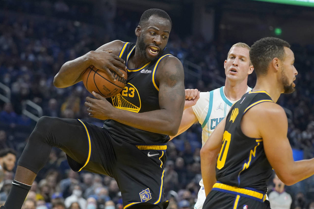 Golden State Warriors forward Draymond Green, left, grabs a rebound in front of Charlotte Hornets c...