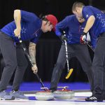 
              From left, Team Shuster's Chris Plys sweeps to curl the rock alongside John Shuster and John Landsteiner while competing against Team Dropkin during the second night of finals at the U.S. Olympic Curling Team Trials at Baxter Arena in Omaha, Neb., Saturday, Nov. 20, 2021. (AP Photo/Rebecca S. Gratz)
            