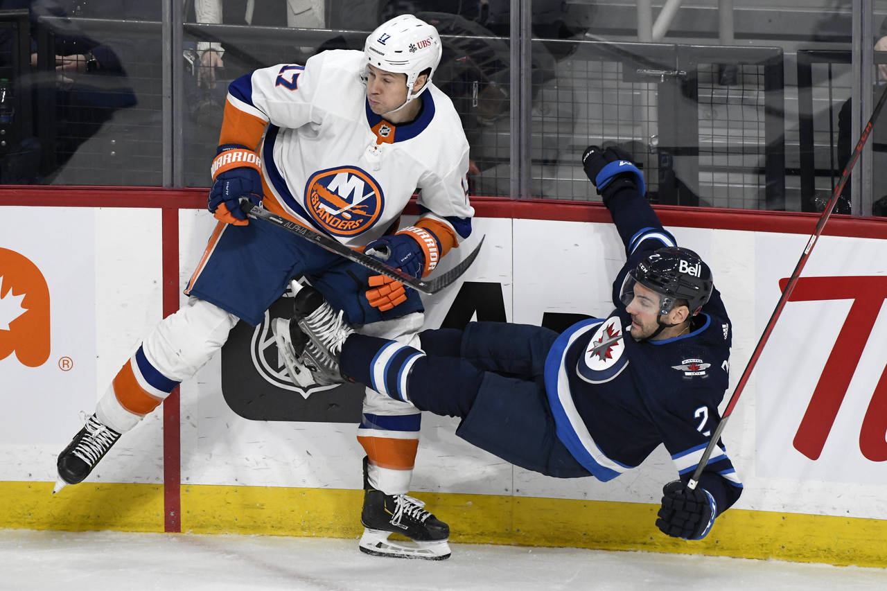 Winnipeg Jets' Dylan DeMelo (2) is checked by New York Islanders' Matt Martin (17) during the first...