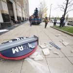 
              Workers from the Brilliant Electric Sign Company put out caution tape as pieces of the Cleveland Guardians team store sign lie on the ground in Cleveland, Friday, Nov. 19, 2021. The sign was being installed and fell off the building.  (AP Photo/Ken Blaze)
            