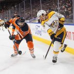 
              Nashville Predators' Philip Tomasino (26) and Edmonton Oilers' Kris Russell (6) vie for the puck during the first period of an NHL hockey game Wednesday, Nov. 3, 2021, in Edmonton, Alberta. (Jason Franson/The Canadian Press via AP)
            