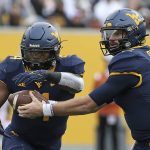 
              West Virginia quarterback Jarret Doege (2) hands the ball off to running back Leddie Brown (4) during the first half of an NCAA college football game against Texas in Morgantown, W.Va., Saturday, Nov. 20, 2021. (AP Photo/Kathleen Batten)
            