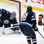 
              Winnipeg Jets goaltender Eric Comrie (1) makes a save against New York Islanders' Scott Mayfield (24) during the first period of NHL hockey game action in Winnipeg, Manitoba, Saturday, Nov. 6, 2021. (Fred Greenslade/The Canadian Press via AP)
            