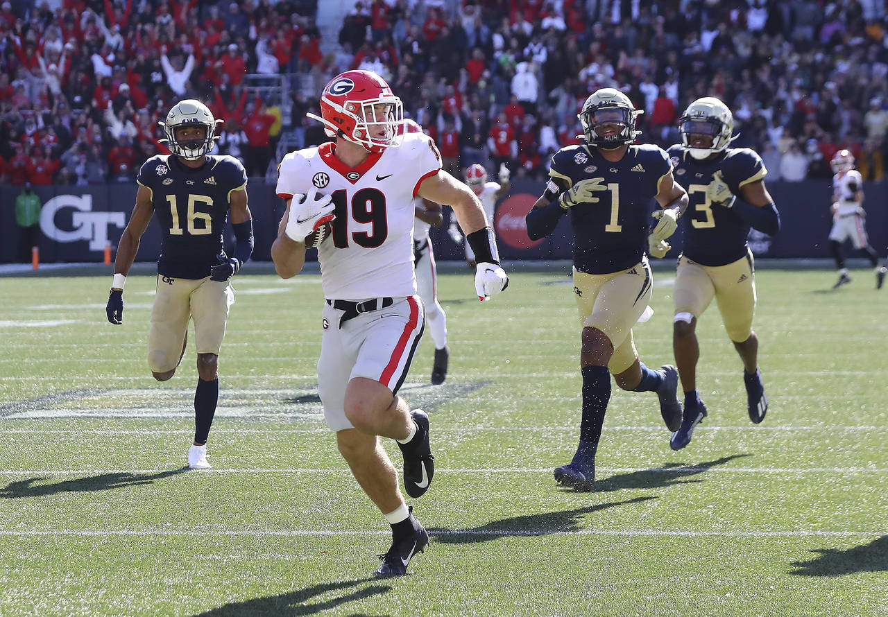 Georgia tight end Brock Bowers looks over his shoulder at Georgia Tech defenders as he heads to the...