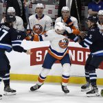 
              New York Islanders' Scott Mayfield (24) grabs Winnipeg Jets' Adam Lowry (17) and Brenden Dillon (5) during the second period of NHL hockey game action in Winnipeg, Manitoba, Saturday, Nov. 6, 2021. (Fred Greenslade/The Canadian Press via AP)
            