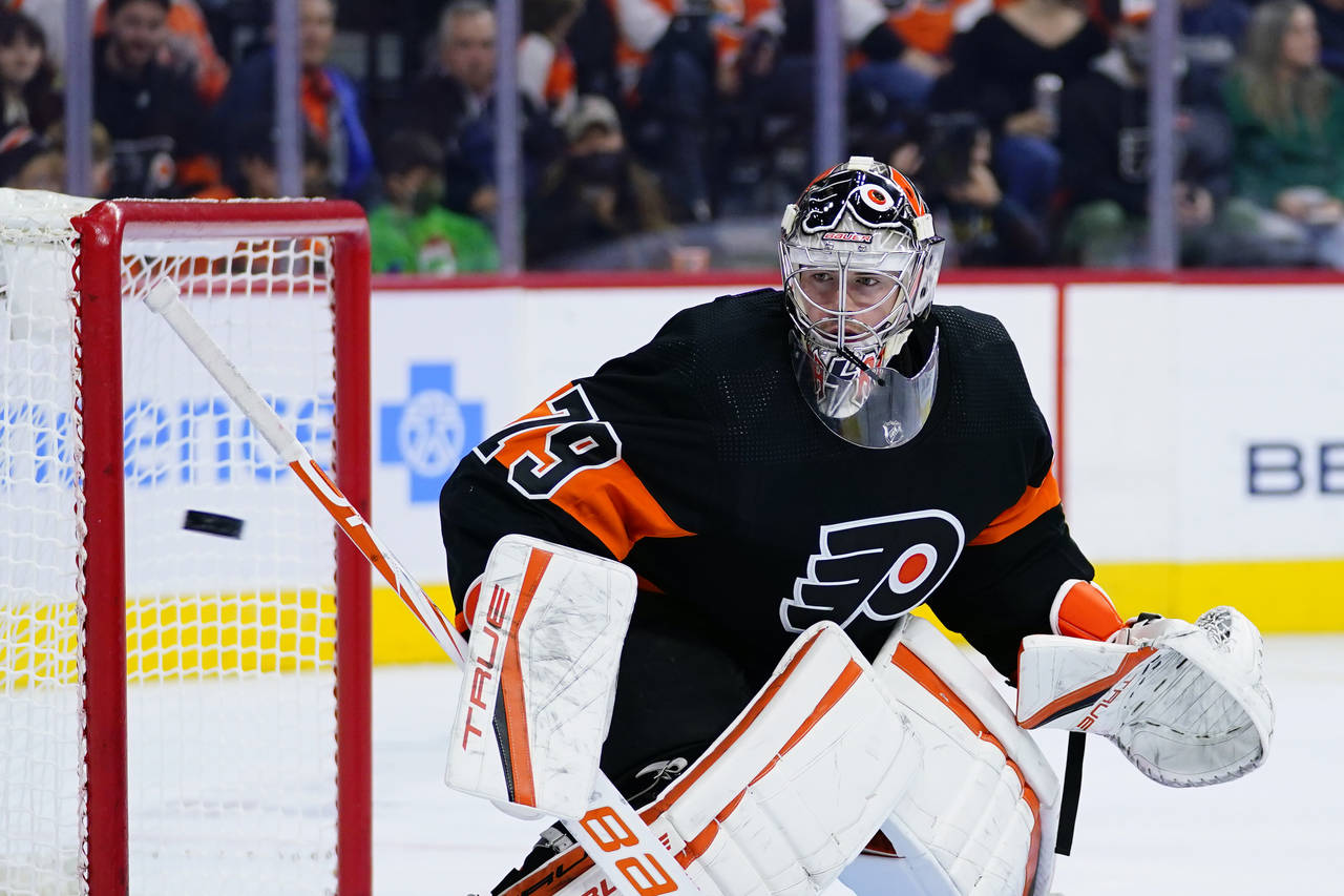 Philadelphia Flyers' Carter Hart watches a shot fly by during the third period of an NHL hockey gam...