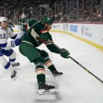 
              Minnesota Wild defenseman Jon Merrill, right, digs the puck out of the corner past Tampa Bay Lightning center Alex Barre-Boulet during the second period of an NHL hockey game Sunday, Nov. 28, 2021, in St. Paul, Minn. (AP Photo/Craig Lassig)
            