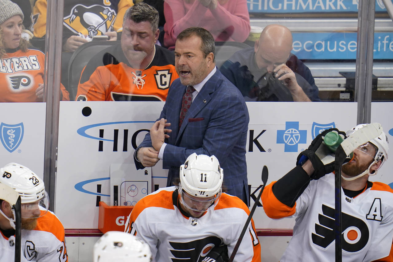 Philadelphia Flyers head coach Alain Vigneault, top center, stands behind his bench during the firs...