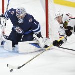
              Winnipeg Jets goaltender Eric Comrie (1) keeps his eyes on the puck as Chicago Blackhawks' Alex DeBrincat (12) attempts a shot during the third period of an NHL hockey game Friday, Nov. 5, 2021, in Winnipeg, Manitoba. (John Woods/The Canadian Press via AP)
            