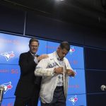 
              Ross Atkins, executive vice president of baseball operations and general manager of the Toronto Blue Jays, helps  Blue Jays pitcher Jose Berrros put on a jersey during a press conference announcing his seven-year extension with the team at Rogers Centre in Toronto, Thursday, Nov. 18, 2021. (Tijana Martin/The Canadian Press via AP)
            