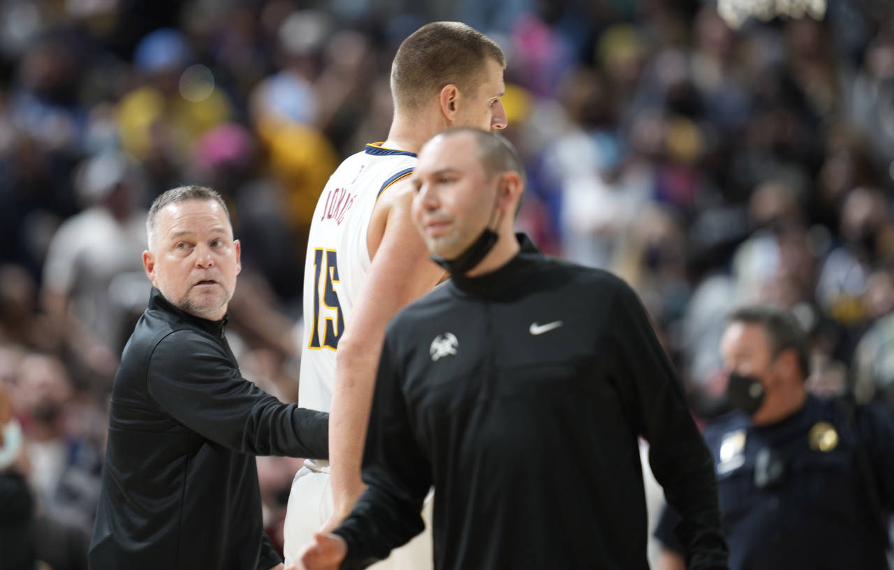 Denver Nuggets head coach Michael Malone, left, guides center Nikola Jokic to the bench after Jokic...