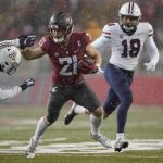 Washington State running back Max Borghi (21) fends off a tackle from Arizona free safety Jaydin Young, left, as he runs for a touchdown and Arizona linebacker Kenny Hebert (18) closes in during the first half of an NCAA college football game, Friday, Nov. 19, 2021, in Pullman, Wash. (AP Photo/Ted S. Warren)