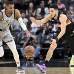 
              Phoenix Suns' Devin Booker, front right, and San Antonio Spurs' Dejounte Murray, left, chase the ball during the first half of an NBA basketball game, Monday, Nov. 22, 2021, in San Antonio. (AP Photo/Darren Abate)
            