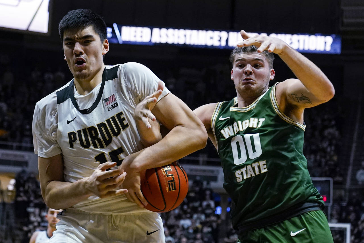 Purdue center Zach Edey (15) and Wright State forward Grant Basile (00) get tied up as they go for ...