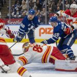 
              Calgary Flames goaltender Dan Vladar (80) dives to cover up the puck as Flames' Rasmus Andersson (4), Nikita Zadorov (16) and Mikael Backlund (11) try to control Toronto Maple Leafs left wing Michael Bunting (58) and center William Nylander (88) during the second period of an NHL hockey game in Toronto on Friday, Nov. 12, 2021. (Frank Gunn/The Canadian Press via AP)
            