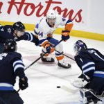 
              Winnipeg Jets' Neal Poink (4) defends against New York Islanders' Jean-Gabriel Pageau (44) who prepares to shoot against Jets goaltender Eric Comrie (1) during the first period of NHL hockey game action in Winnipeg, Manitoba, Saturday, Nov. 6, 2021. (Fred Greenslade/The Canadian Press via AP)
            
