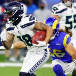 INGLEWOOD, CALIFORNIA - DECEMBER 21: Freddie Swain #18 of the Seattle Seahawks carries the ball as Christian Rozeboom #56 of the Los Angeles Rams defends in the second quarter of the game at SoFi Stadium on December 21, 2021 in Inglewood, California. (Photo by Ronald Martinez/Getty Images)