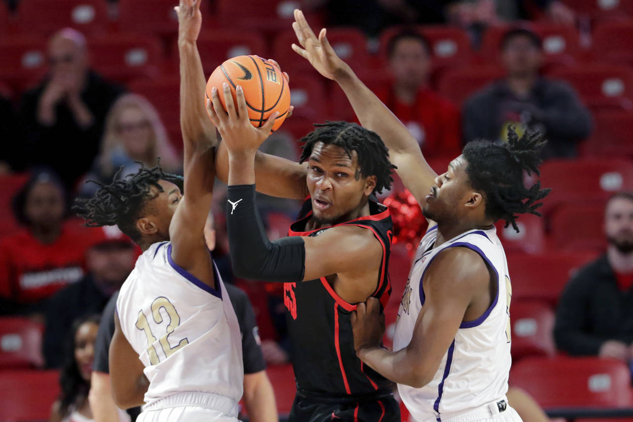 Houston center Josh Carlton, center, looks to pass the ball from between Alcorn State guards Dekedr...